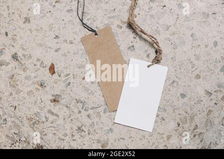Empty paper gift tags, price labels with ropes on terrazzo background. Marble stone texture. Modern template, branding identity. Summer vacation Stock Photo