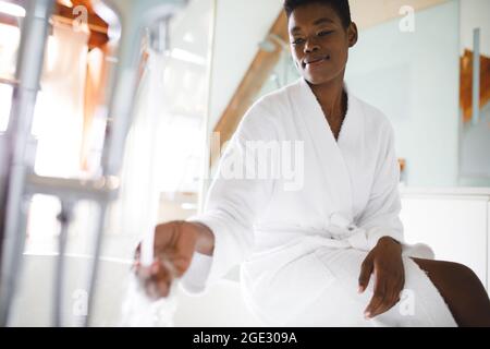 Smiling african american woman in bathroom running a bath Stock Photo