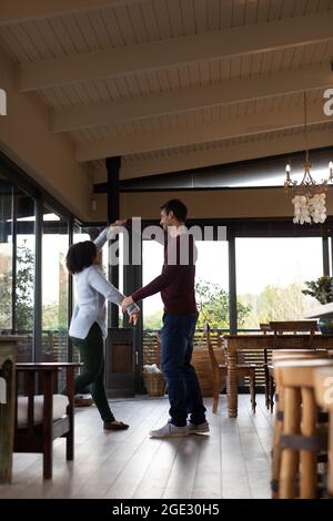 Happy diverse couple in living room dancing together and smiling Stock Photo