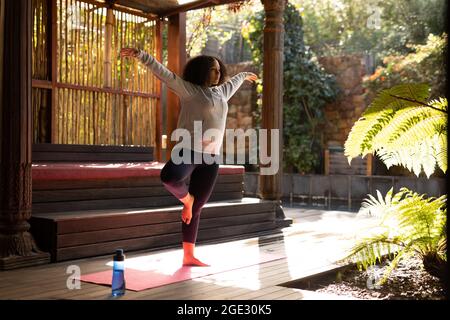 Mixed race woman wearing sportswear and practicing yoga on yoga mat Stock Photo