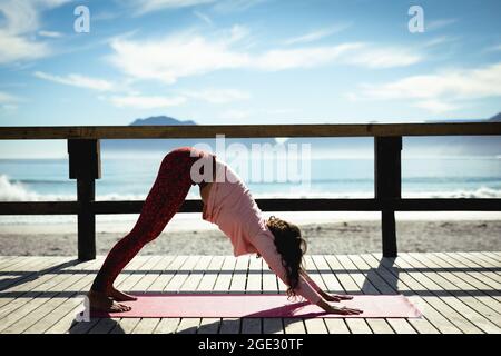 Mixed race woman practicing yoga on sunny day by seaside Stock Photo