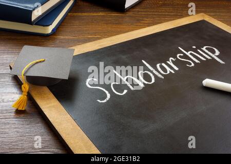 Scholarship written on the blackboard and graduation cap. Stock Photo