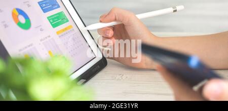 Banner worker analyzing company perfomance on digital tablet pc using stylus pen. Business and financial diagram on the screen, office desk background Stock Photo