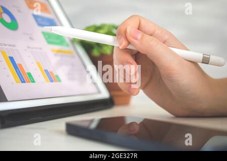 Worker analyzing company perfomance on digital tablet pc using stylus pen. Business and financial diagram on the screen, office desk background photo Stock Photo