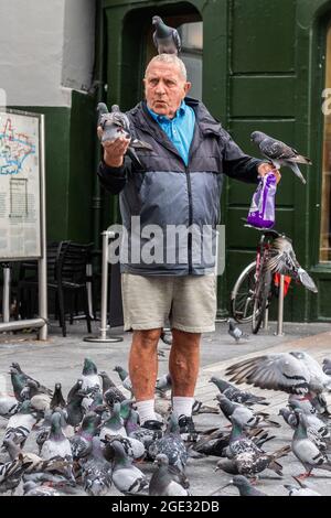 Cork, Ireland. 16th Aug, 2021. Frank O'Flaherty from Gurranabraher was feeding the pigeons in Daunts Square, Cork City Centre. Credit: AG News/Alamy Live News Stock Photo