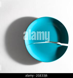 Rift - the beginning; Crack in blue plate on white background, rift between two parts Stock Photo