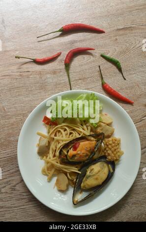 fried spicy seafood spaghetti with basil leaf topping mussel dressing chili sauce on plate Stock Photo