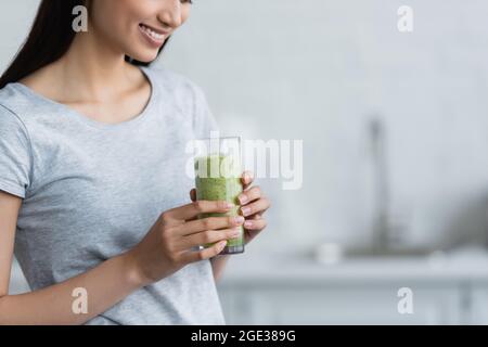 partial view of smiling woman holding glass of fresh homemade smoothie Stock Photo