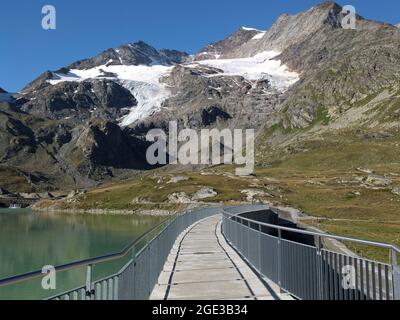 Dam wall between Lago Bianco and Lej Nair on the Bernina massif in Switzerland, below Piz Cambrena Stock Photo