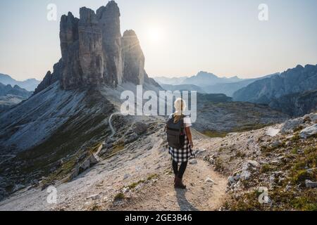 Women hiker with backpack enjoying the Tre Cime di Lavaredo during sunset. Dolomites, Italy Stock Photo