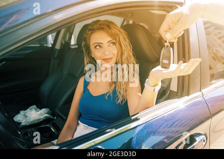 young and beautiful woman take the key from valet to drive her car. High quality photo Stock Photo