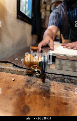 Unrecognized luthier working in his atelier and making a guitar. He is using a special tools. Stock Photo