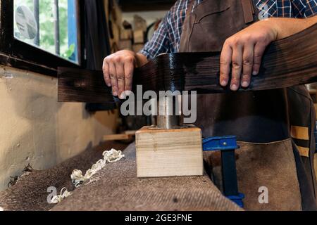 Unrecognized luthier creating a guitar in his workshop and using tools. Stock Photo