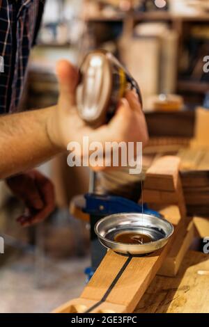 Unrecognized luthier creating a guitar and using tools in a traditional workshop. Stock Photo
