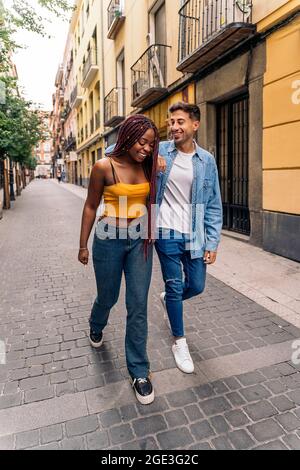 Cheerful multi-ethnic young couple walking in the streets of Madrid and having fun. Stock Photo