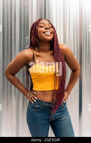 An African young woman with braids posing and smiling on a pink ...