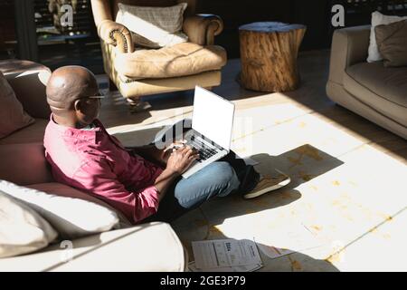 Senior african american man in modern sunny living room working on laptop Stock Photo