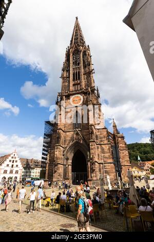 Freiburg, Germany. 16th Aug, 2021. People stand on Freiburg's Münsterplatz in front of the cathedral. Freiburg Cathedral is formally a cathedral, as Freiburg has been an episcopal see since 1827. The Archdiocese of Fribourg was formally established by Pope Pius VII on 16 August 1821 with the bull 'Provida solersque'. Credit: Philipp von Ditfurth/dpa/Alamy Live News Stock Photo