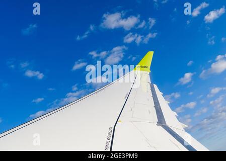 Estonia, 31.06.2021 AirBaltic Plane wing with logo in cloudy sky Stock Photo