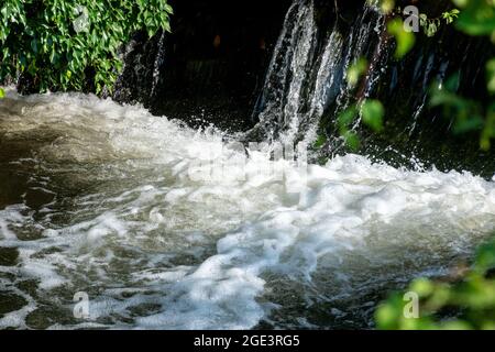 Whitewater at the base of a small wier where water cascades over. Stock Photo