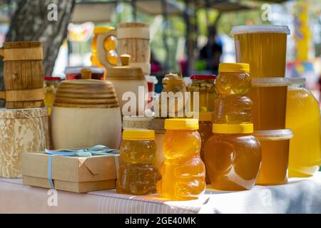 Bee honey is packaged in glass, plastic and wooden containers and is ready for sale on the market. Stock Photo