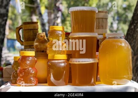 Bee honey is packaged in glass, plastic and wooden containers and is ready for sale on the market. Stock Photo