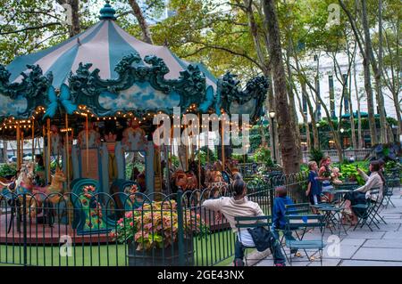 Children riding a carousel in the Winter Village at Bryant Park, Manhattan, New York City.  People enjoying in Bryant Park a City park in Mid-town Man Stock Photo