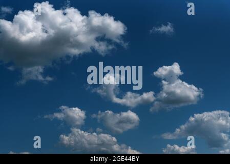 Dark blue sky and white clouds natural background. White cumulus clouds in the blue sky. Stock Photo