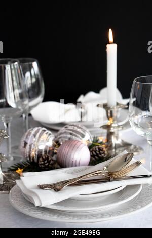 Christmas table setting with white napkins, antique sliver cutlery and candleholders Stock Photo