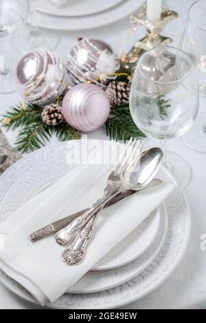 Christmas table setting with white napkins, antique sliver cutlery and candleholders Stock Photo