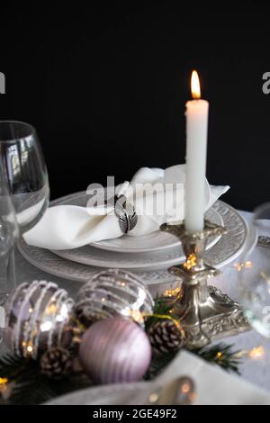 Christmas table setting with white napkins, antique sliver cutlery and candleholders Stock Photo