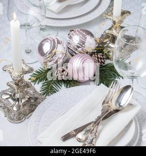 Christmas table setting with white napkins, antique sliver cutlery and candleholders Stock Photo