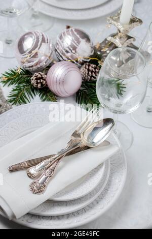 Christmas table setting with white napkins, antique sliver cutlery and candleholders Stock Photo