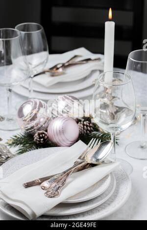 Christmas table setting with white napkins, antique sliver cutlery and candleholders Stock Photo