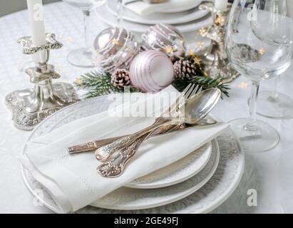 Christmas table setting with white napkins, antique sliver cutlery and candleholders Stock Photo