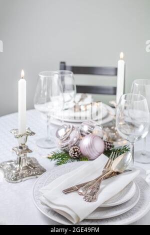 Christmas table setting with white napkins, antique sliver cutlery and candleholders Stock Photo