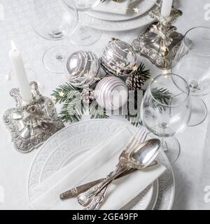 Christmas table setting with white napkins, antique sliver cutlery and candleholders Stock Photo