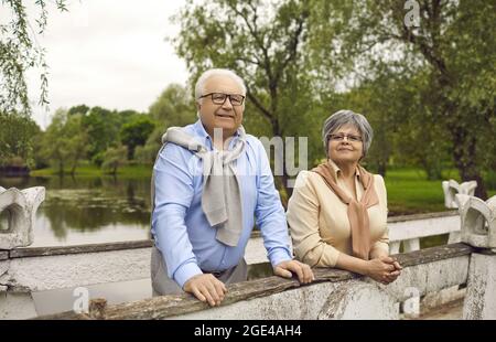 Portrait of happy retired couple relaxing standing on bridge enjoy rest in park Stock Photo