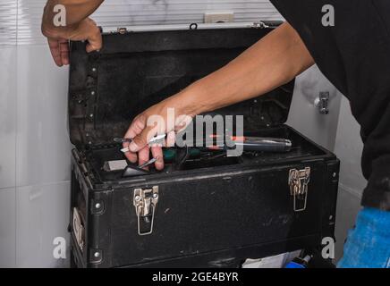 Hans of a man looking for tools in a toolbox Stock Photo