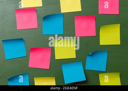 Many blank colorful memory stickers on a dark green background. The empty space on multi-colored office stickers. Busy day, business concept. Stock Photo