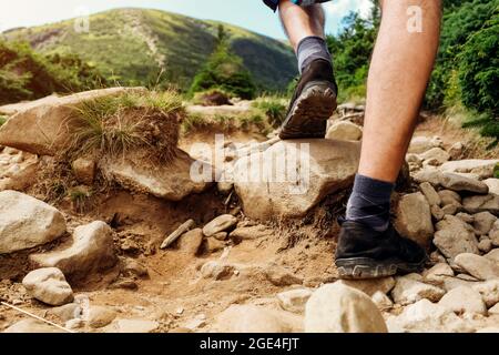 Hiking in Carpathian mountains. Close up of hiker's shoes. Man climbing on Hoverla walking on rocks . Traveling in summer Ukraine Stock Photo