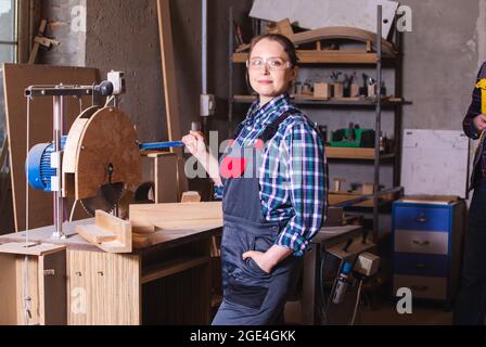 Female employee of woodworking plant operating circular saw Stock Photo
