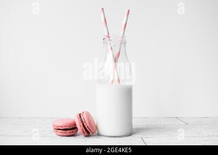 Small glass milk bottle with pink candy stripe paper straws and pink  macarons Stock Photo - Alamy