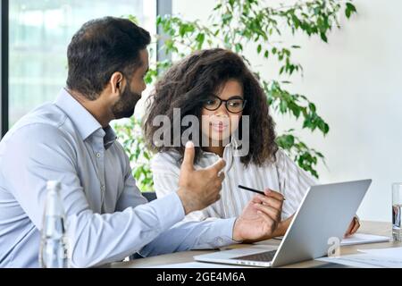 Indian ceo businessman banker talking to female client using laptop at meeting. Stock Photo