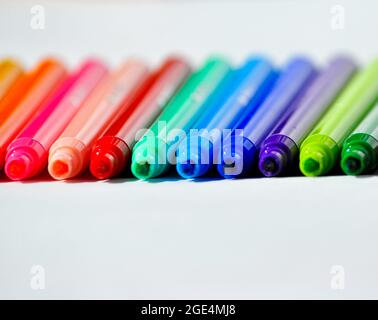 Rainbow colour of felt tip pens without lids on. Colours are lined up against a white background. Stock Photo