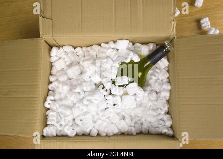 Wine bottle in fragile delivery package top view, opened mail with champange bottle, service,delivery,transport,alcohol concept Stock Photo