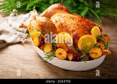 Christmas food. Baked turkey garnished with potato, oranges and  cranberries on a wooden table Stock Photo
