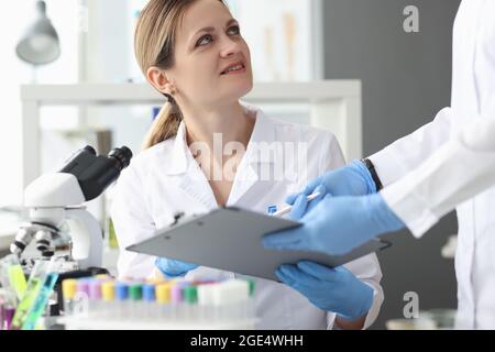 Scientists in laboratory use microscope and record results closeup Stock Photo