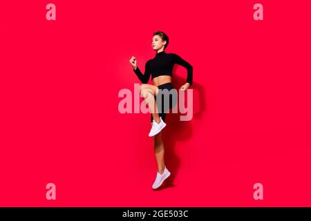 Profile photo of runner serious lady jogging training wear black cropped top isolated red color background Stock Photo