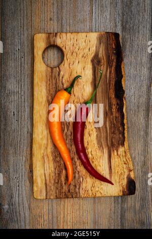 two pods of hot pepper on a wooden cutting board Stock Photo